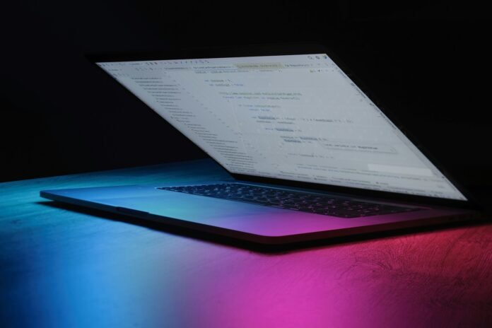 Neon ışıklı ekranda kod görünen laptop, yapay zeka ve yazılım geliştirme teması