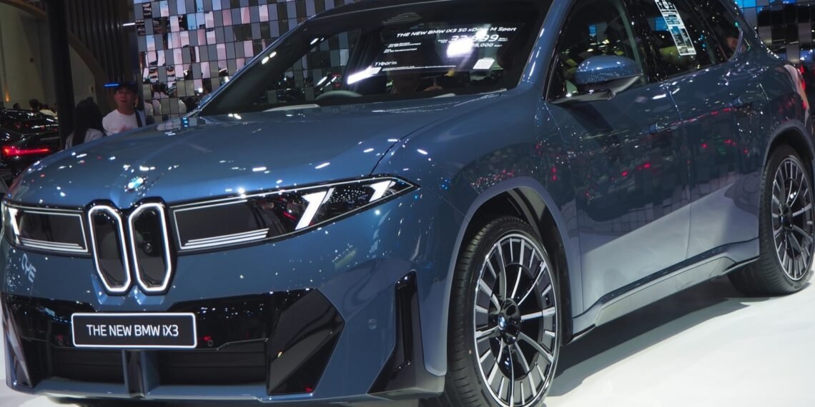 Otomobil fuarında önden görünen mavi 2026 BMW iX3 50 xDrive M Sport