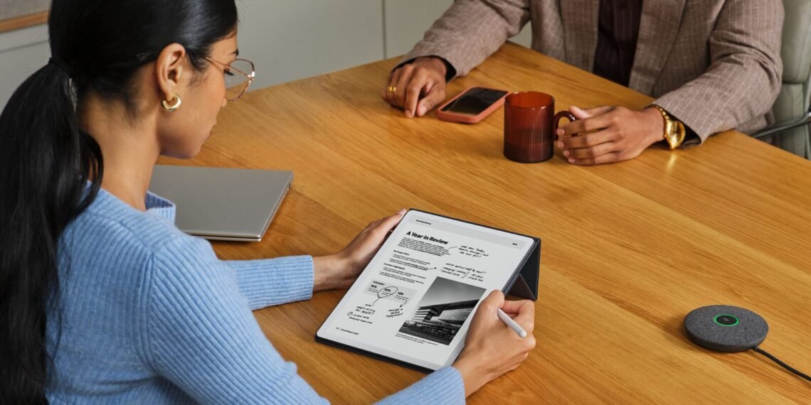 Toplantı masasında Kindle Scribe Colorsoft ile kalem kullanarak not alan kişi