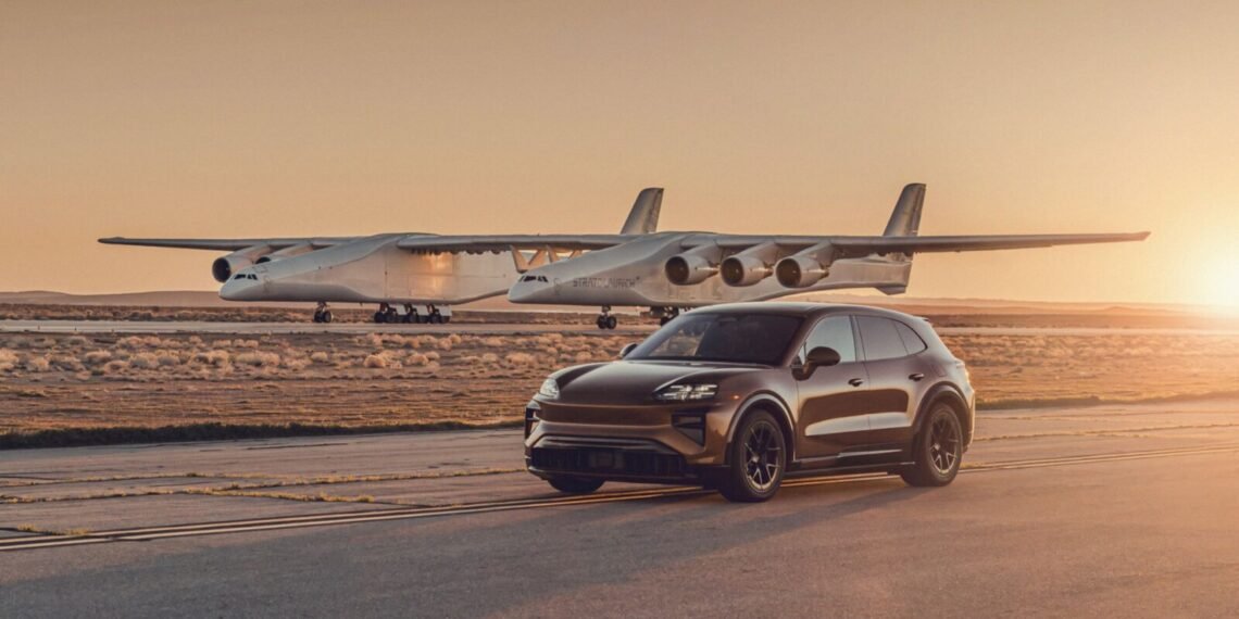 Pistte Porsche Cayenne Turbo Electric ve arkasında Stratolaunch Roc uçağı