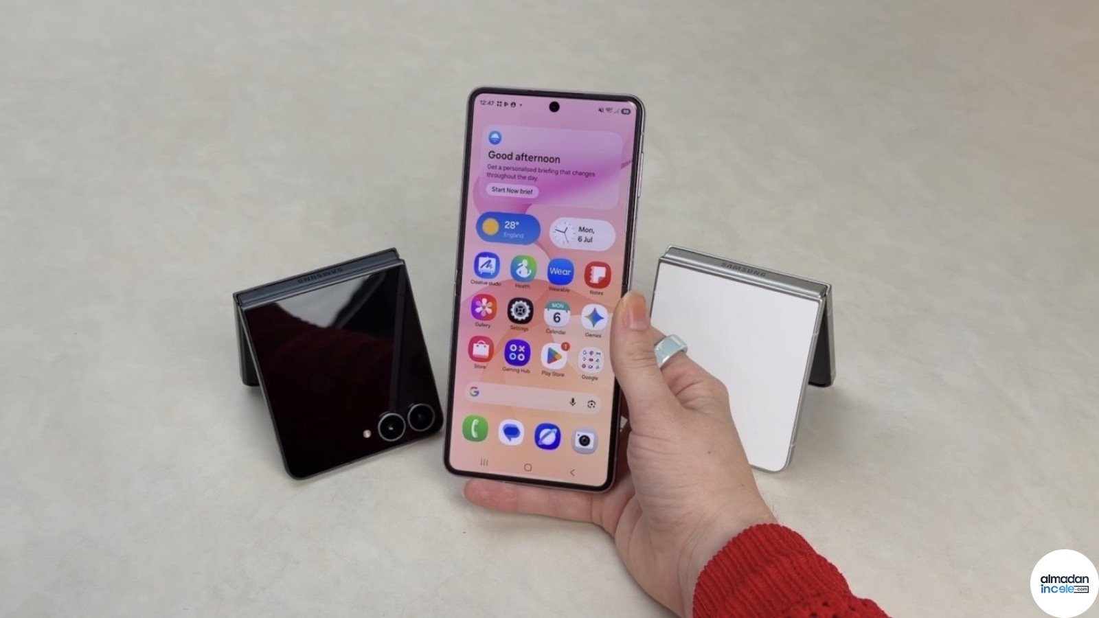 Elde açık tutulan pembe Samsung Galaxy Z Flip8 ve arka planda katlanmış modeller