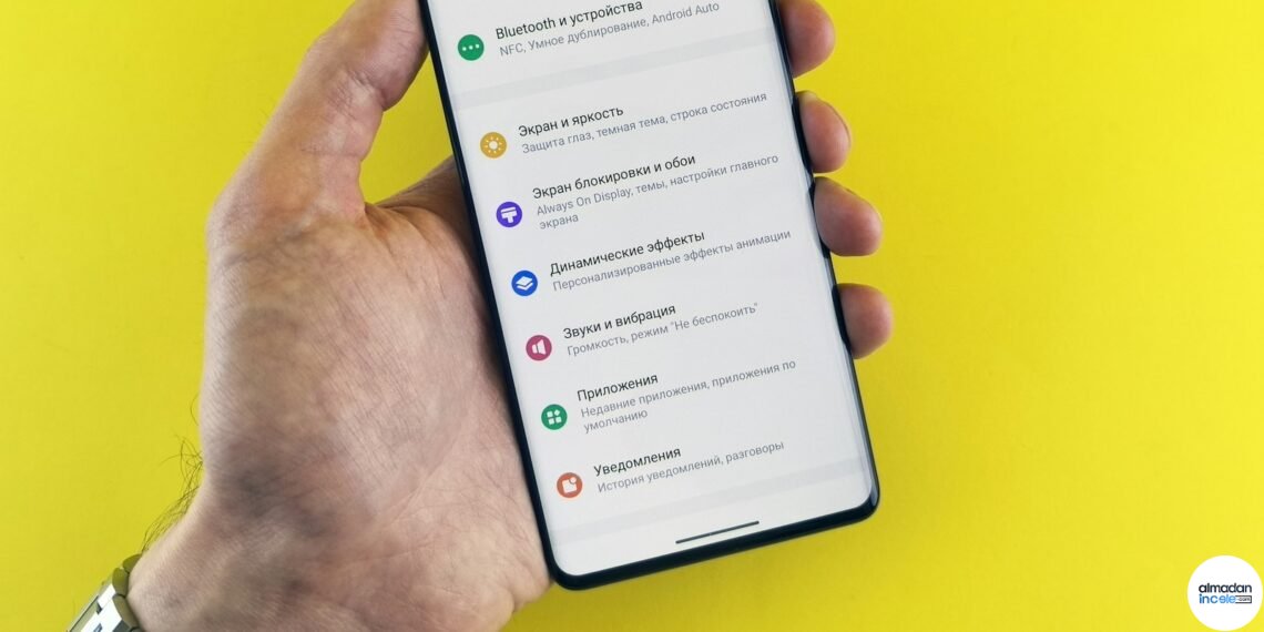 Ayarlar ekranı açık akıllı telefonu tutan el; Android güvenlik yaması kontrol adımlarını anlatan rehber görseli
